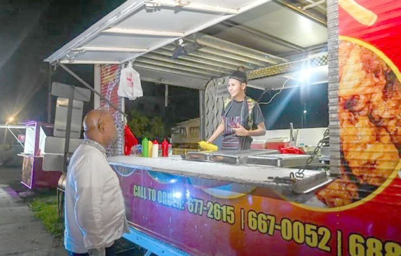 Minister of Public Works, Bishop Juan Edghill, engages a food-truck worker on Friday