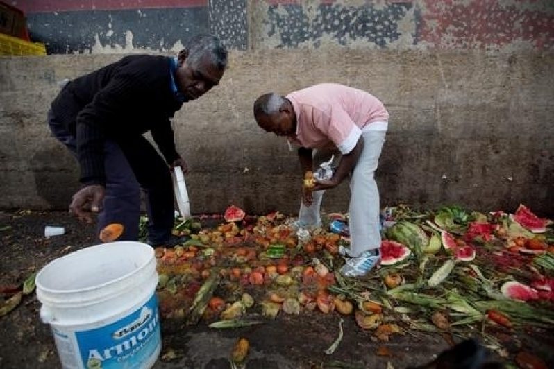 In this May 31, 2016 photo, Pedro Hernandez, left, and his friend Luis Daza, pick up tomatoes from the trash area of the Coche public market in Caracas, Venezuela. (Photo: AP)