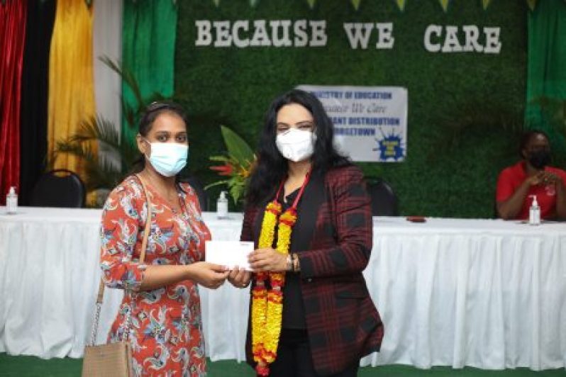 A parent collects the grant from Minister of Human Services and Social Security, Dr. Vindhya Persaud, at the Graham’s Hall Primary School on Tuesday (DPI photo)