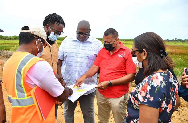 CH&PA Chief Executive Officer, Sherwyn Greaves (centre); Housing and Water Minister, Collin Croal (second right), contractors and staff peruse the plan during the site visit