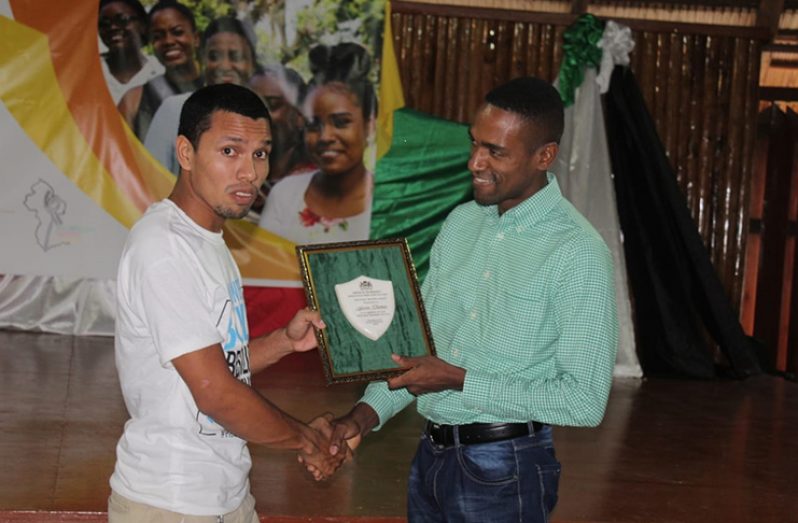 One volunteer, Gavin Thomas receives his award of recognition from Liaison Officer for The United Nations Population Fund (Guyana) Alder Bynoe