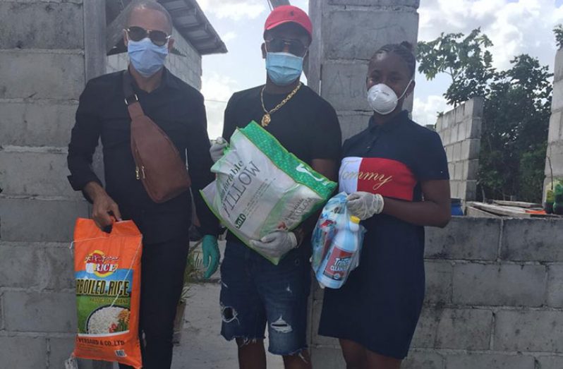 Director of Vybz Entertainment, Damuka Ngqondo (extreme left) and other members of the group during the distribution of hampers to over 100 families in Linden