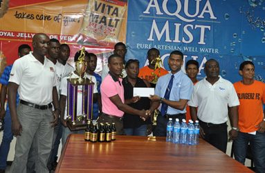Aqua Mist Brand Manager Errol Nelson (4th right) hands over the sponsorship cheque to WDFA President Nigel Garraway. Also present of Vita Malt Brand Manager Clayton McKenzie, Communications Manager Troy Peters, players and other officials.