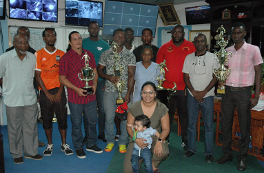 Prize winners pose with their hardware along with Brian Tiwari’s daughter and grandson (stooping) at the company’s head office on Monday.