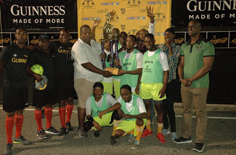 Guinness representative Evlon Hendy hands over the first prize and winning trophy to Melanie ‘B’ captain Ryan Seales in the presence of teammates, referees and Guinness Brand Manager Lee Baptiste (right) during the presentation ceremony.