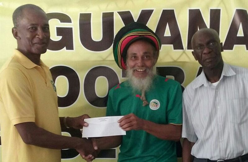 GFF's Executive Committee member Keith O'Jeer on behalf of GFF presents cheque to chief tournament organiser, Ras Wadada, in the presence of GFF General Secretary (Ag), Trevor King.