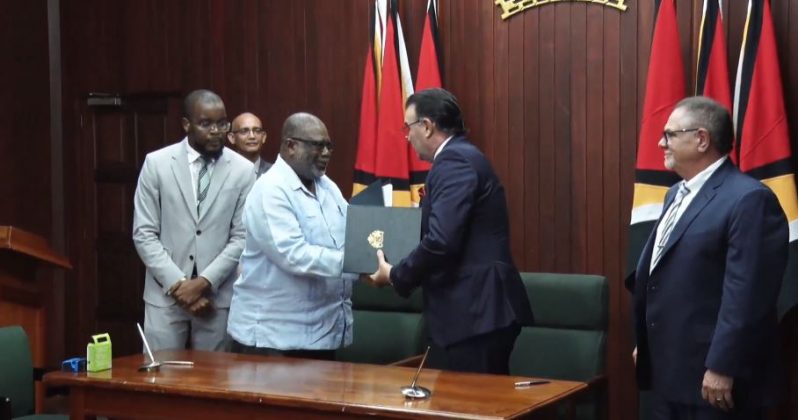 Representatives of Guyana and the contracting company sign the agreement.