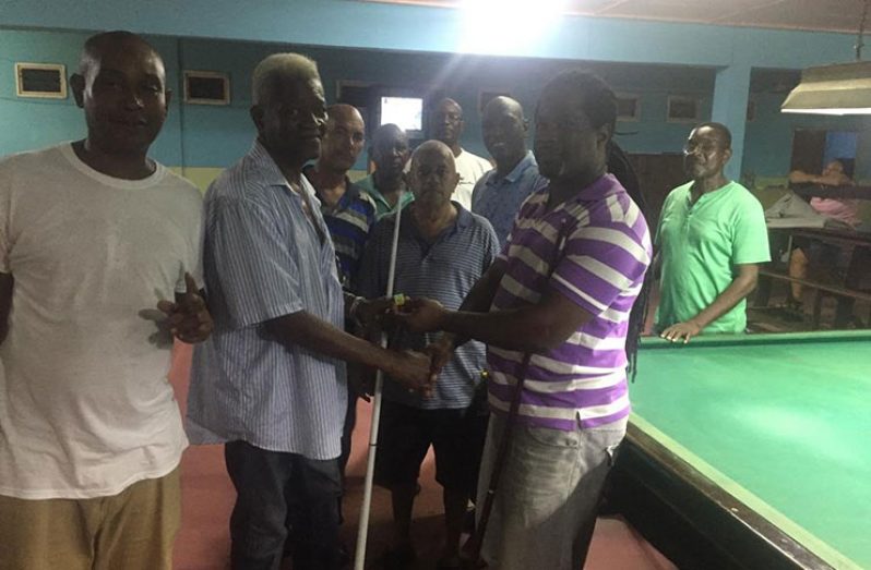 Hardcourt Warde, second from left, hands over billiards chalk to Troy Roberts.