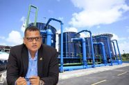 Minister of Housing and Water, Collin Croal and, in the background, the Wales Water Treatment Plant which was commissioned recently