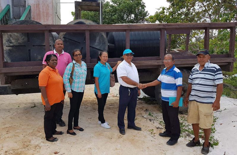 Regional Executive Officer, Denis Jaikaran handing over the tanks to residents of the community