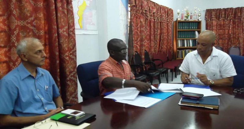 Minister of Communities Ronald Bulkan observes Permanent Secretary Emil Mc Garrell and CEO of Ashmins Fun Park and Resort Lennox John sign the agreement, yesterday