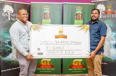 Water Beverages Manager Colin King presents a ceremonial cheque to Romario Samaroo of FL Sport