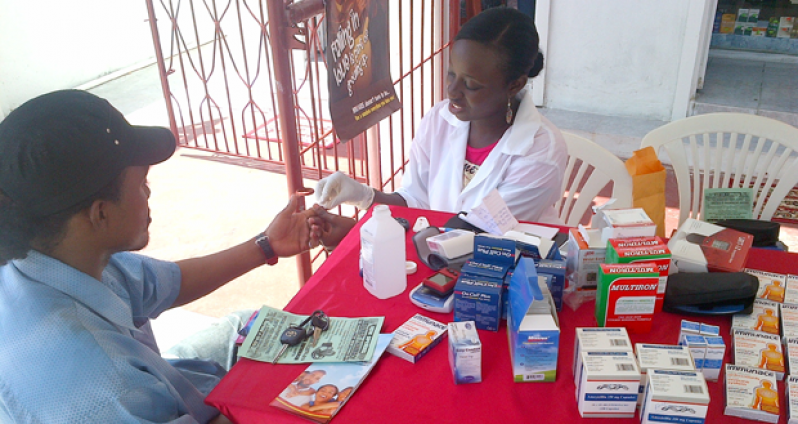 Welmart Pharmacy proprietor Ayanna Blair administering a blood test to a citizen