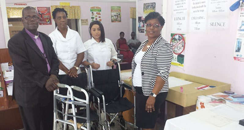 Bishop Timothy Norton of God’s Cathedral of Praise (at left) presents the two wheelchairs and a walker to Medex Karen Sears (right). Looking on are nurses Dawn Miller and Anne Marie Hudson
