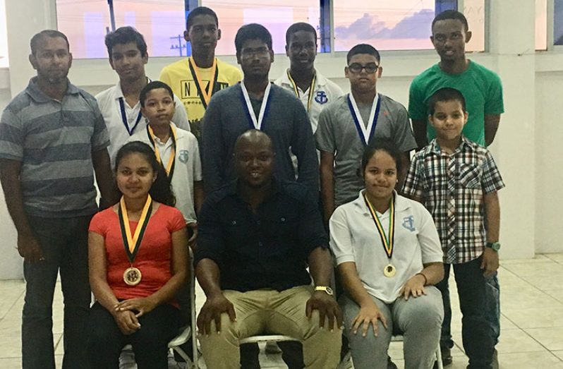 President of the Guyana Chess Federation, James Bond, vice-president – tournament, Irshad Mohamad, and committee member Anthony Drayton pose with the top eight qualifiers and Joshua Williams, the youngest player at age eight.