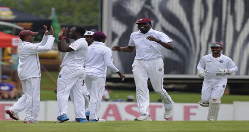 West Indies celebrate the opening breakthrough when Kemar Roach, seen here receiving a high-five from Shiv Chanderpaul, removed Alviro Petersen. (AFP)