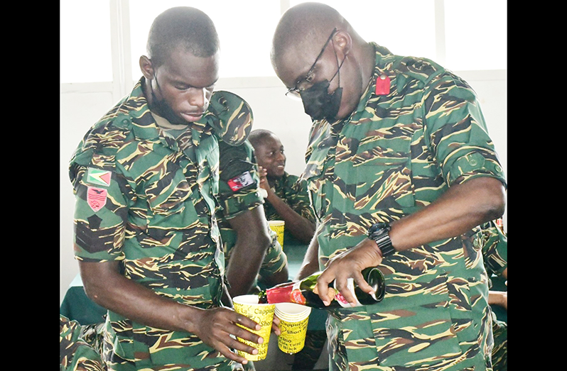 Colonel Skeete pours some non-alcoholic wine for a soldier on Soldiers' Day