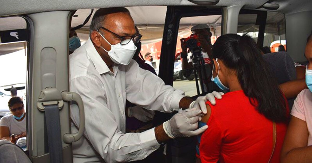 Health Minister, Dr. Frank Anthony, administering a jab of the Pfizer-BioNTech COVID-19 vaccine to a child during the COVID-19 drive through at the MovieTowne parking lot, East Coast Demerara on Sunday (Elvin Croker photo)