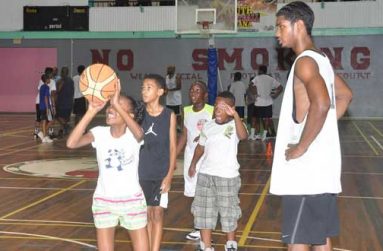 National point guard Akeem Kanhai looks on as a YBG camp participant tries to execute what she was taught (Delano Williams photo)