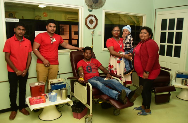 A donor is flanked by members of the WCD branch of the Young Pioneers (Adrian Narine photo)