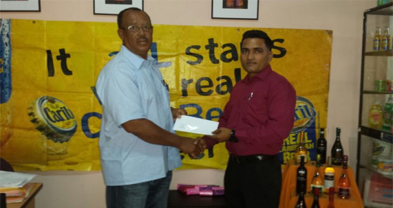 YWCC senior coach Hubern Evans receives the sponsorship cheque from Marketing Representative Imran Khan.