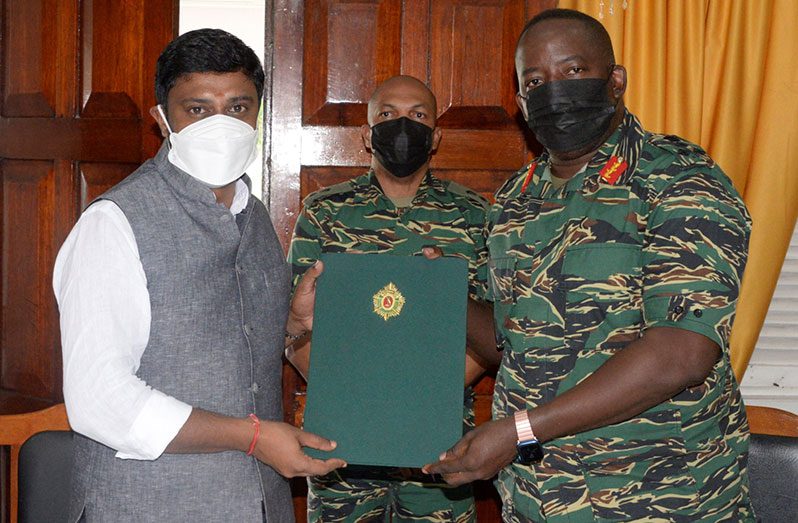 Chief of Staff, Brigadier Godfrey Bess and Founder and President of the TAU, Saju Bhaskar, holds up the signed agreement as a soldier looks on (GDF photograph)