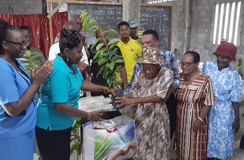 Minister Valerie Adams-Yearwood handing a soursop tree and hamper to an elderly Victorian