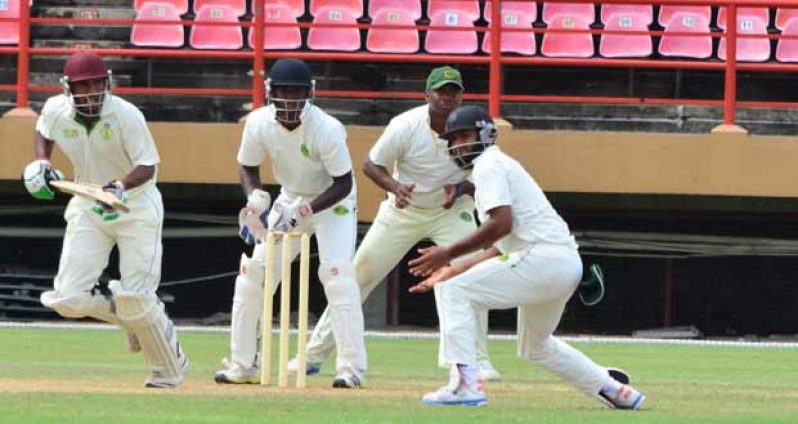 Guyana’s Anthony Bramble (wicketkeeper) and Christopher Barnwell (slip) looks on as Windward Islands top scorer Romel Currency plays one past Assad Fudadin at forward short leg during yesterday’s action. (Photo by Adrian Narine)