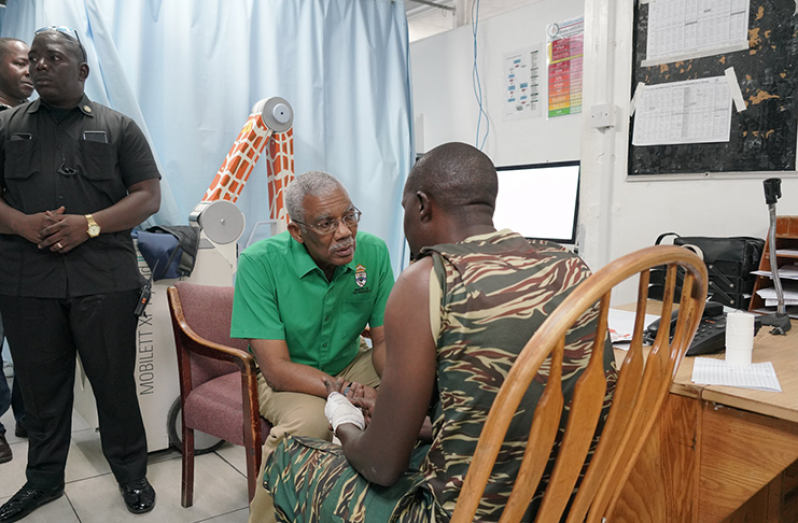 President David Granger interacts with an injured rank of the Guyana Defence Force.