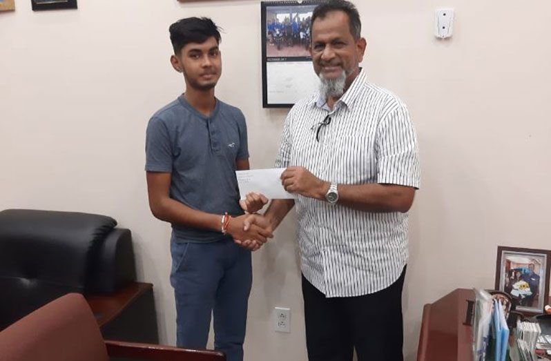 Managing Director of Mohamed's Enterprise, Nazar Mohamed presenting young Parmesh Ramgobin with a cheque to help finance his tertiary studies