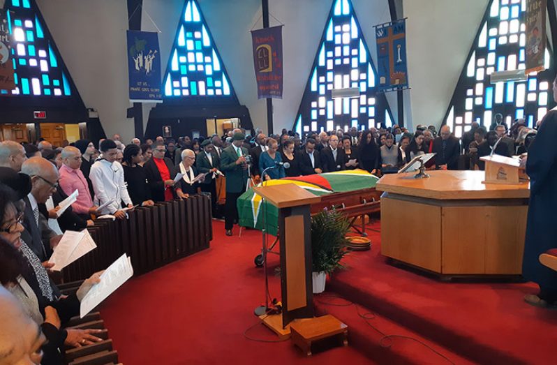 A section of the congregation with the flag-draped casket in the background