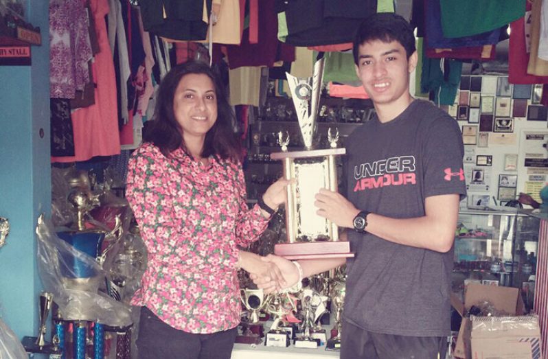 Trophy Stall representative  Mrs Davi Sunich (left) hands over one of the trophies to defending Men’s singles champion Narayan Ramdhani, who collects on behalf of the GBA.