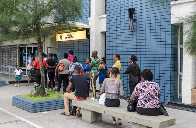 Customers at a Republic Bank ATM on Monday (Delano Williams photo)