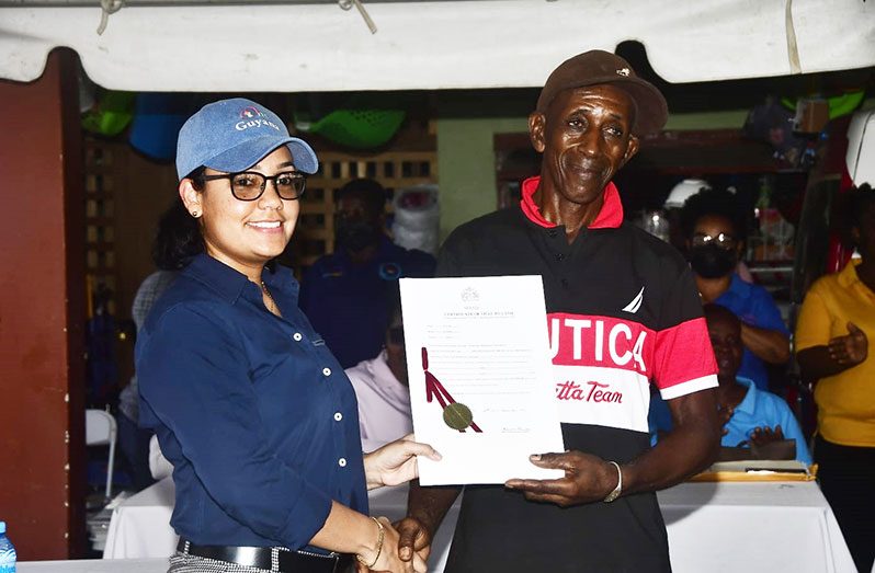 An elated Sheldon Younge receives his certificate of title from Minister within the Housing and Water Ministry, Susan Rodrigues (Adrian Narine photos)