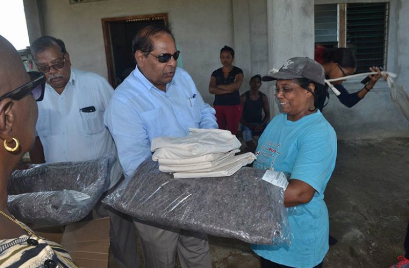 Prime Minister Moses Nagamootoo hands over blankets and other items to this resident of Bath Settlement