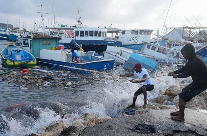Fishermen pull a boat damaged by Hurricane Beryl back to the dock at Bridgetown Fisheries in Barbados (Associated Press)