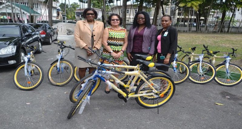 First Lady, Mrs. Sandra Granger, is flanked by from left, Lt. Col. (Ret'd), Ms. Yvonne Smith, from the Office of the First Lady; Universal Group of Companies' Administrative Manager, Ms. Nevica Wray; and Operations Officer, Ms. Toanna Greene, at the presentation ceremony. The donated bicycles are also pictured (Ministry of the Presidency photo)