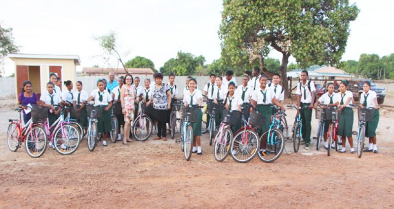 First Lady Mrs. Sandra Granger and Minister of Social Cohesion, Amna Ally stand among the students of St. Ignatius Secondary School as they display their new bikes