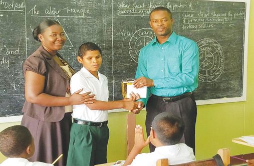 Visually impaired student Roll Sumner receiving the audio recorder from Mayor of Linden Carwyn Holland. Giving support is visually impaired teacher from Wismar -Hill Primary School, Shellin Saving