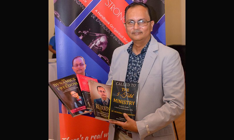 Dr. Ravindra Shiwnandan displays his books (Delano Williams photo)