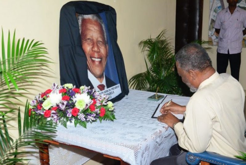 Prime Minister Samuel Hinds signing the book of condolence for the late South African President, Nelson Mandela, at the National Cultural Centre