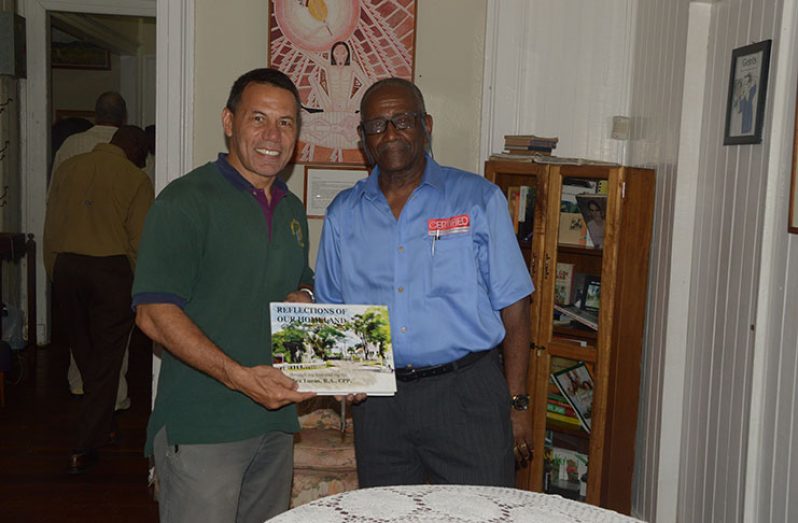 Photographer and Author, Rex Lucas handing over an autographed copy of his book to a purchaser (Adrian Narine photo)