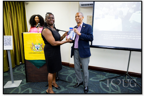 Professor Compton Bourne, OE, presents a copy of his book to Dr Simone Bernard, Acting University Librarian