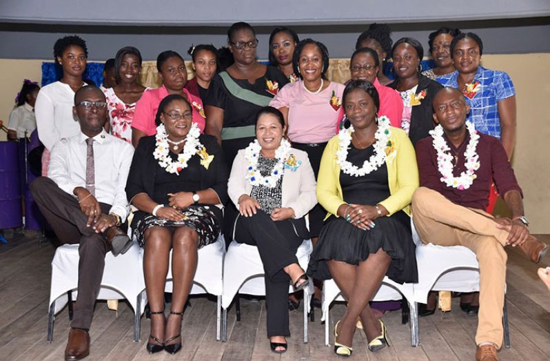 Minister of State, Mrs. Dawn Hastings Williams (seated, centre) is flanked by, from left to right seated: GTU Buxton Branch official, Mr. Collis Nicholson; GTU General Secretary, Ms. Coretta McDonald; Acting Regional Education Officer (REO), Department of Education Region Four, Ms. Tiffany Harvey and Chairperson of the Regional Education Committee (REC), Mr. Ryan Belgrave. Other members of the GTU Buxton branch are pictured standing