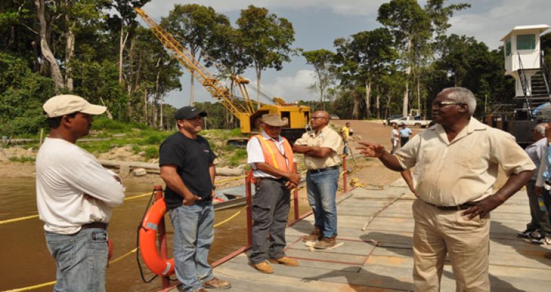 Public Works Minister Robeson Benn gives a briefing, standing on the makeshift barge at the Essequibo River-end, Section Two of the Amaila Falls Access Road