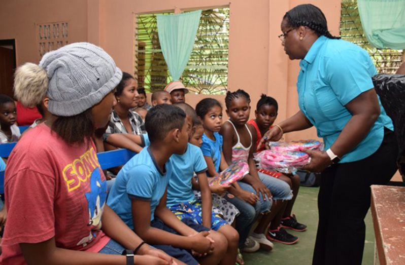 Minister Broomes distributing backpacks and stationery to the children of Victory Valley
