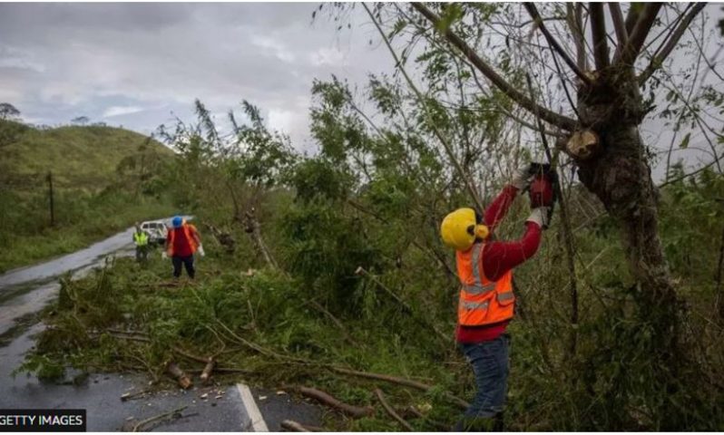 Workers remove fallen trees from the highway in the northeast of the Dominican Republic after Hurricane Fiona on 21 September