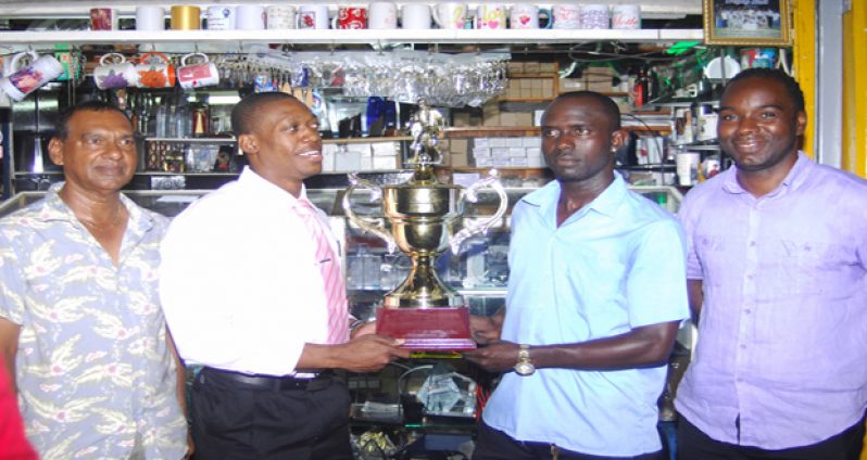 Captains of tonight's FUTSAL final holding the Trophy Stall sponsored winners' trophy; at left is Kerwin Clarke of the Ministry of Foreign Affairs and at right, Phillip Rowley of Banks DIH. At extreme left is Ramesh Sunich Managing Director of Trophy Stall, and far right is Tournament Organiser Esaun Griffith