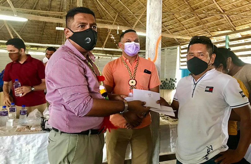 A resident receives his cash grant from Agriculture Minister, Zulfikar Mustapha, and Natural Resources Minister, Vickram Bharrat, looks on