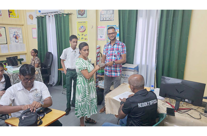 Dr Ritesh Tularam hands over the education grant to the parent of a Region Two CAPE student